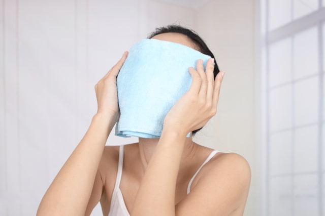 蒸しタオルで顔を覆う女性